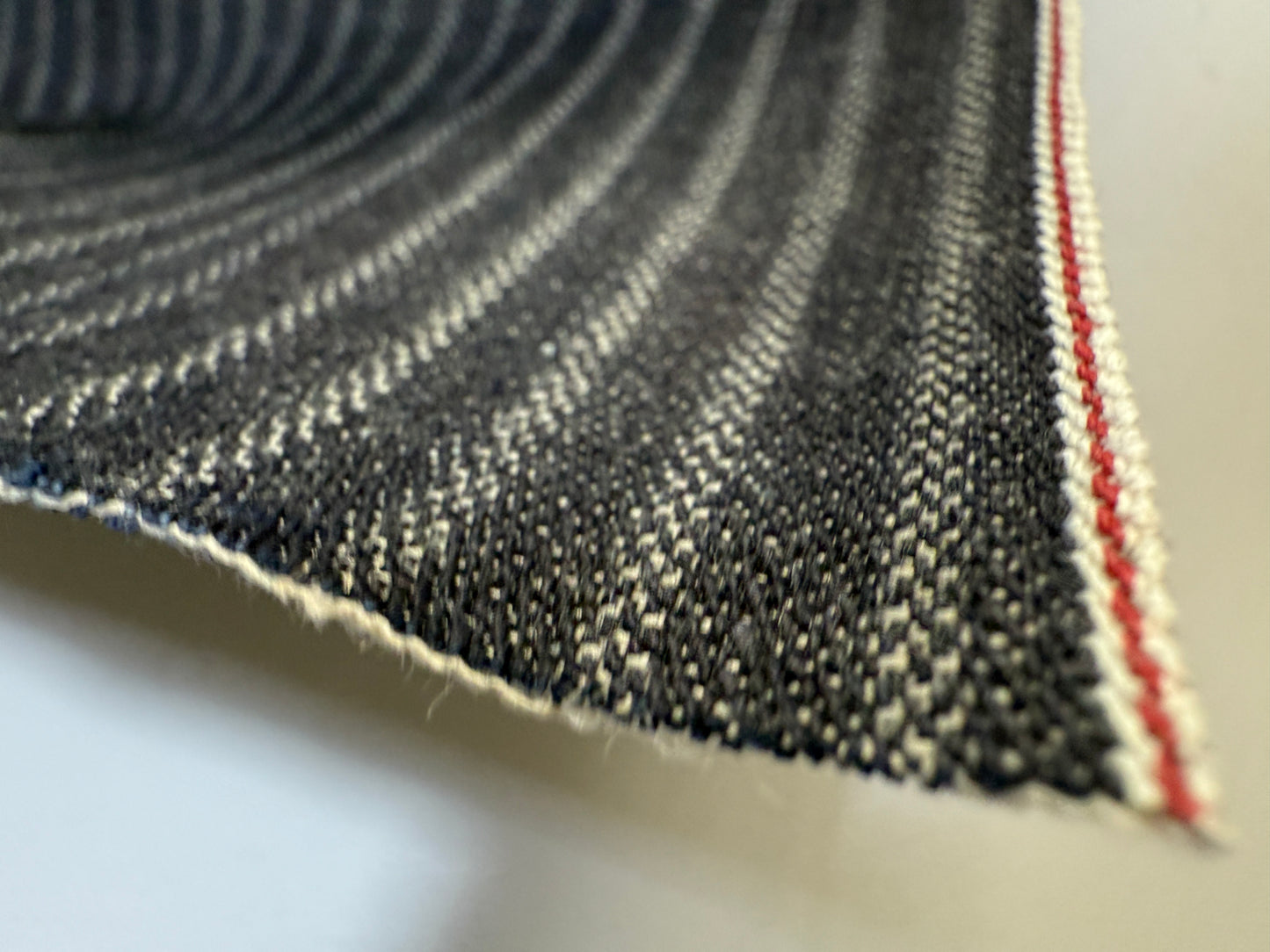 Close-up of Okayama Denim 11.3oz Black Selvedge Hickory fabric displaying classic workwear stripe and detailed edge.