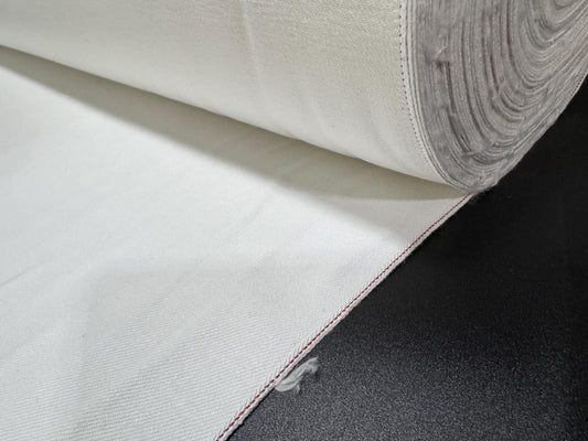 Okayama Denim 13 oz White Selvedge fabric with red edge rolled on a black surface.
