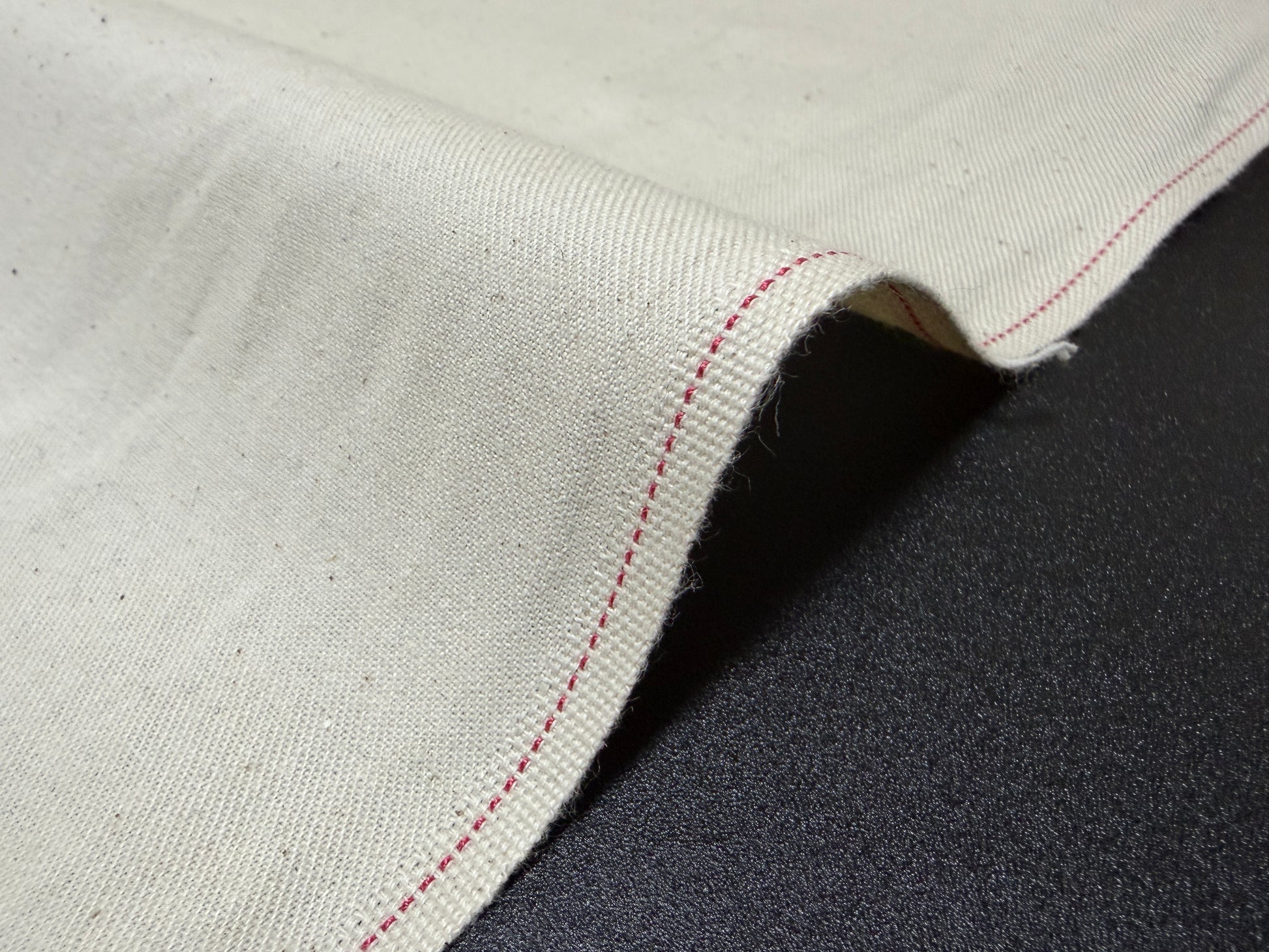 Okayama Denim Cotton Slake Fabric with red stitching detail, ideal for jeans pockets, showcasing natural cotton texture.