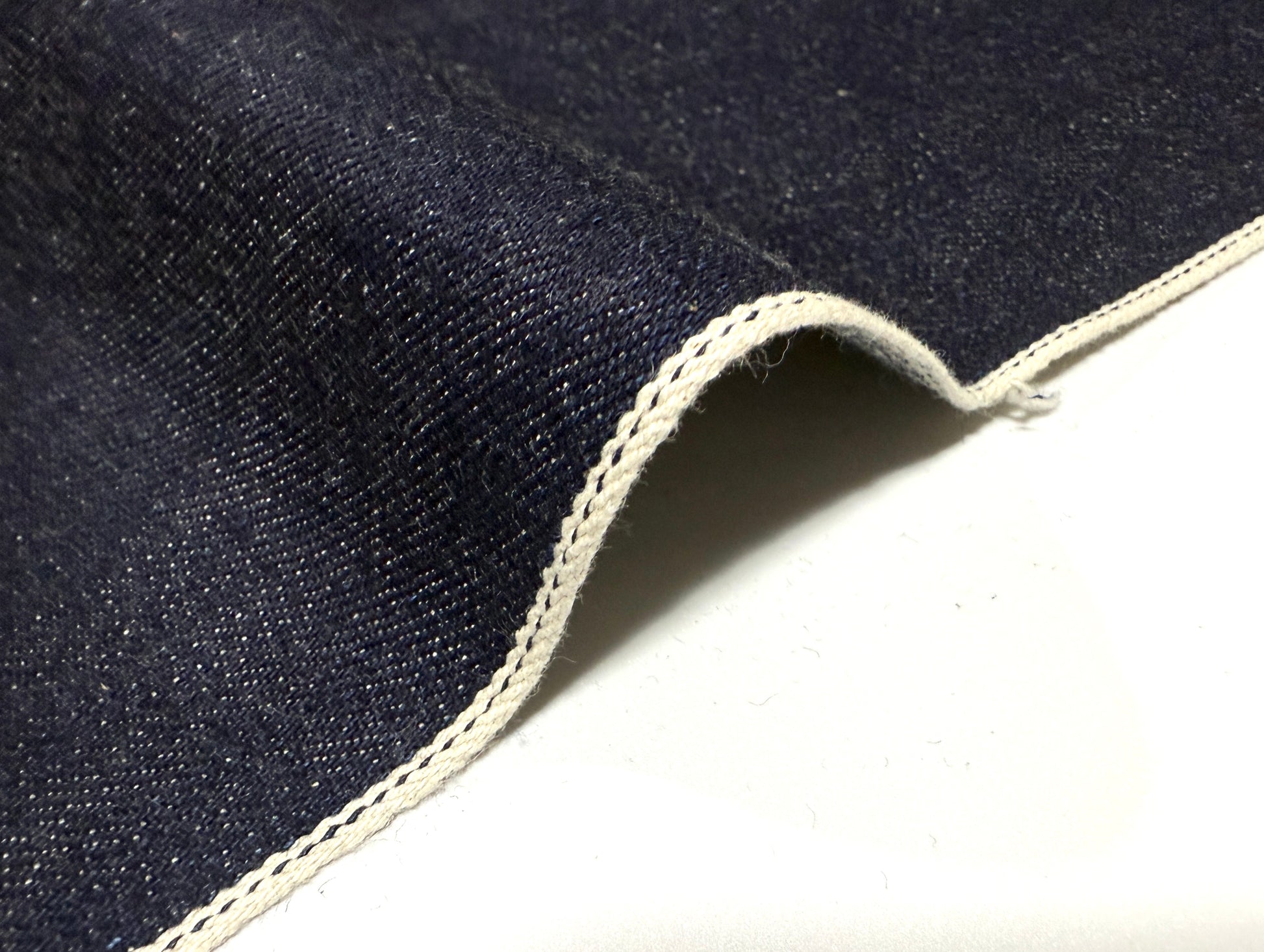 Okayama Denim | 13 oz Japanese Indigo Kibata Selvage Denim fabric showcasing the selvedge edge and rich blue color.