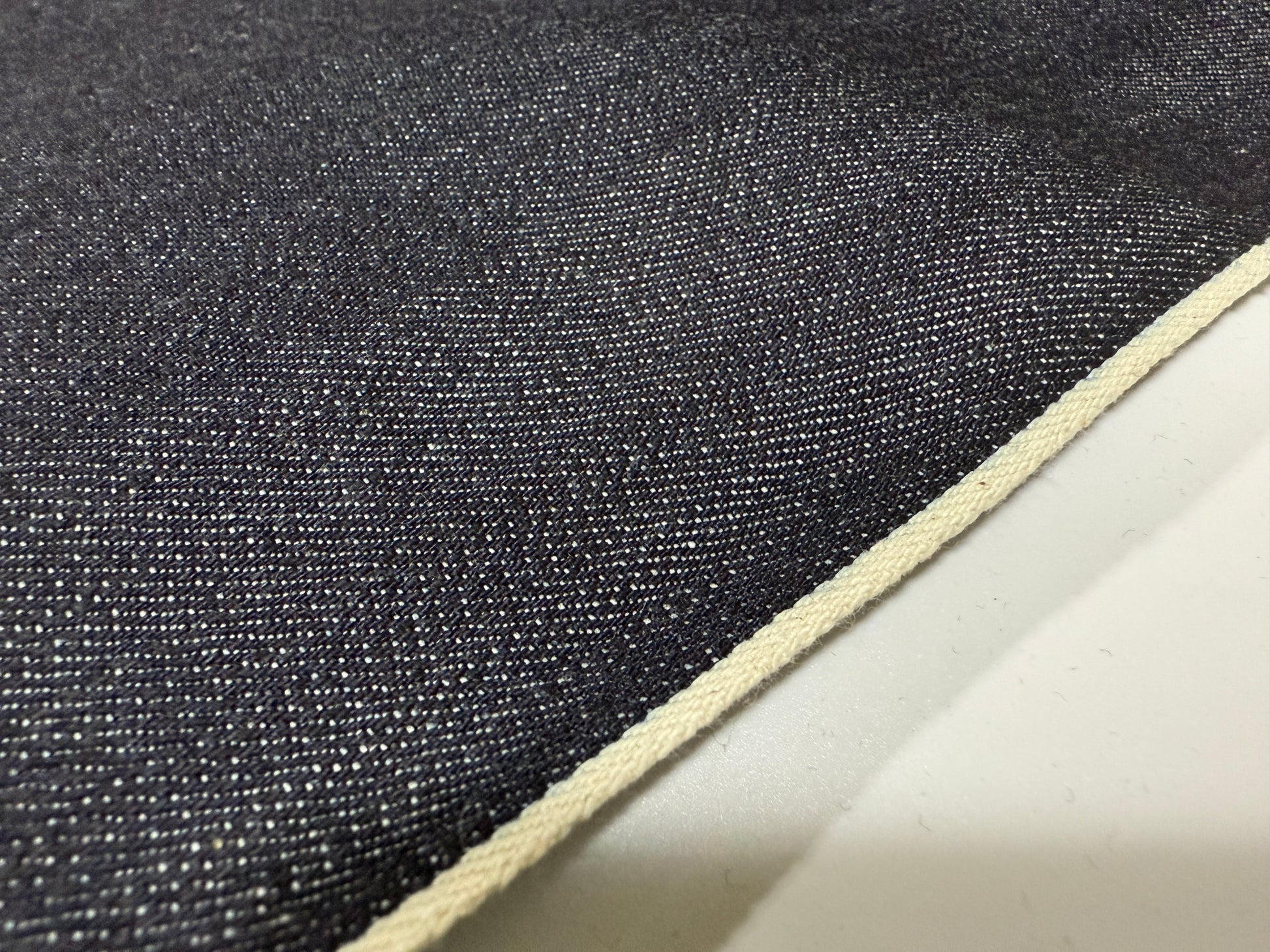 Close-up of Okayama Denim | 12.5 oz Indigo Japanese selvedge denim fabric showcasing texture and white selvage edge.