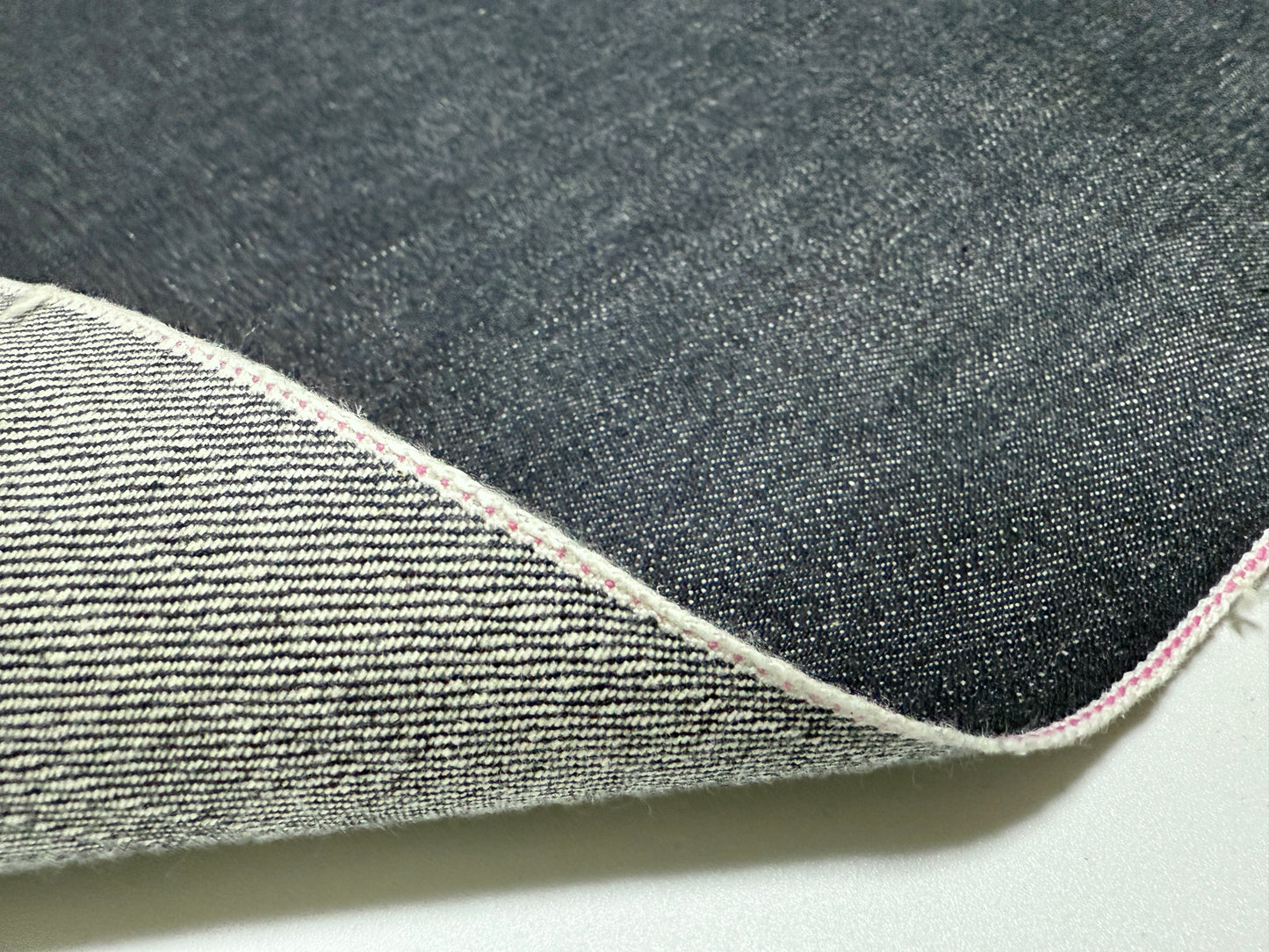 Okayama Denim | Close-up of 13.5 oz indigo kibata Japanese selvage fabric with pink selvage edge.
