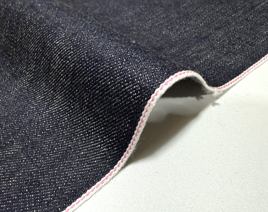 Okayama Denim 13.5 oz indigo kibata Japanese selvage fabric showing pink selvage edge on a white background.