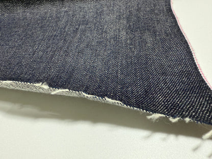 Close-up of Okayama Denim 13.5oz indigo kibata Japanese selvage fabric showcasing its raw texture and pink selvage.