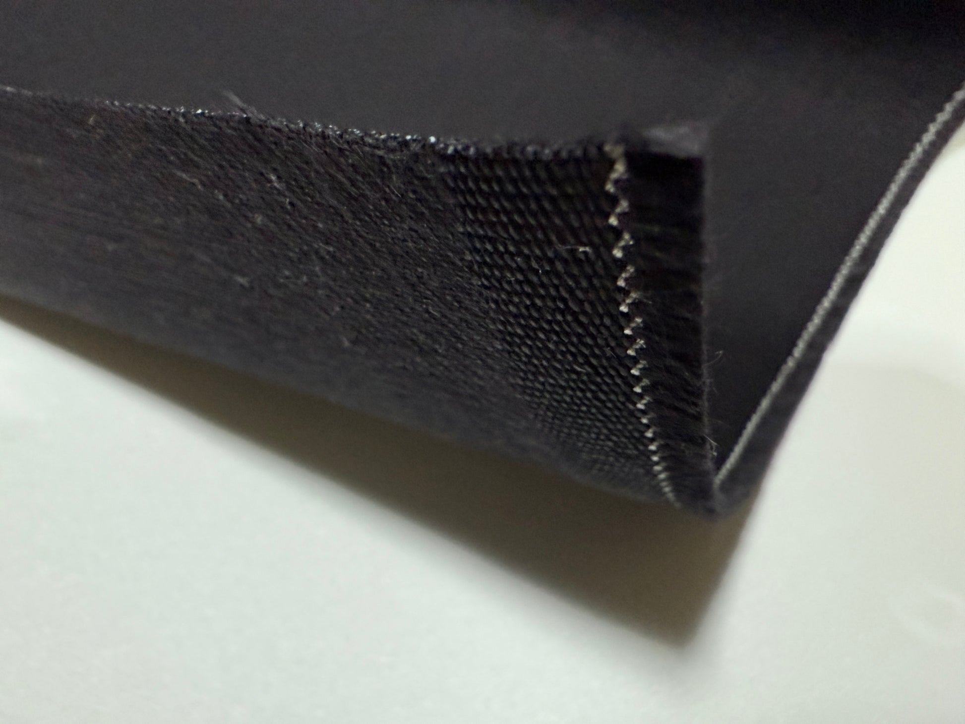 Close-up of Okayama Denim | 13.3oz double-sided black denim fabric showcasing its texture and edge.