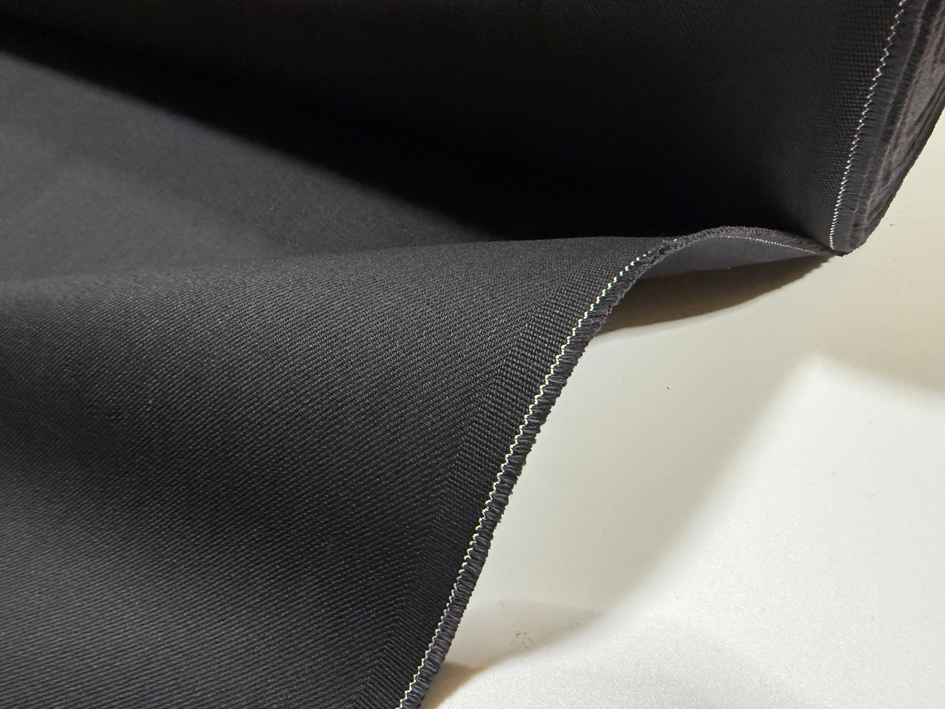 Okayama Denim | 13.3oz double width double-sided black denim fabric showcasing its smooth twill texture.