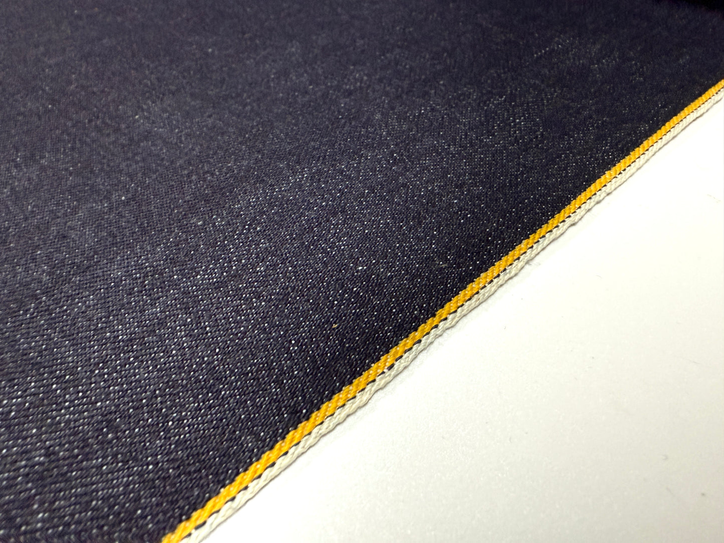 Okayama Denim | Close-up of 13 oz indigo kibata Japanese selvage denim fabric with yellow selvage detailing.