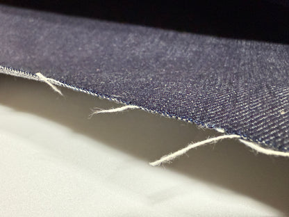 Okayama Denim 13 oz indigo kibata Japanese selvage denim fabric close-up showing raw edge and texture.