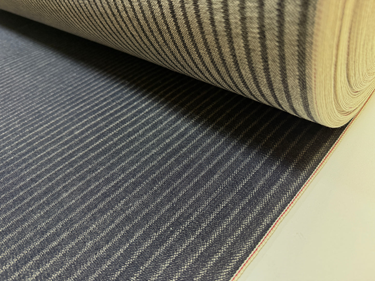 Okayama Denim roll showcasing 11.3 oz Black Selvedge Hickory fabric with distinctive workwear stripe pattern.
