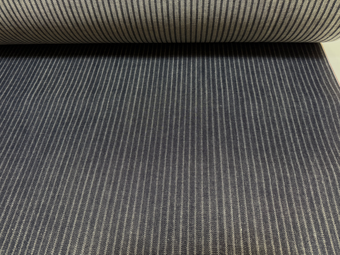 Okayama Denim black hickory selvage fabric roll showing fine stripes and smooth texture.