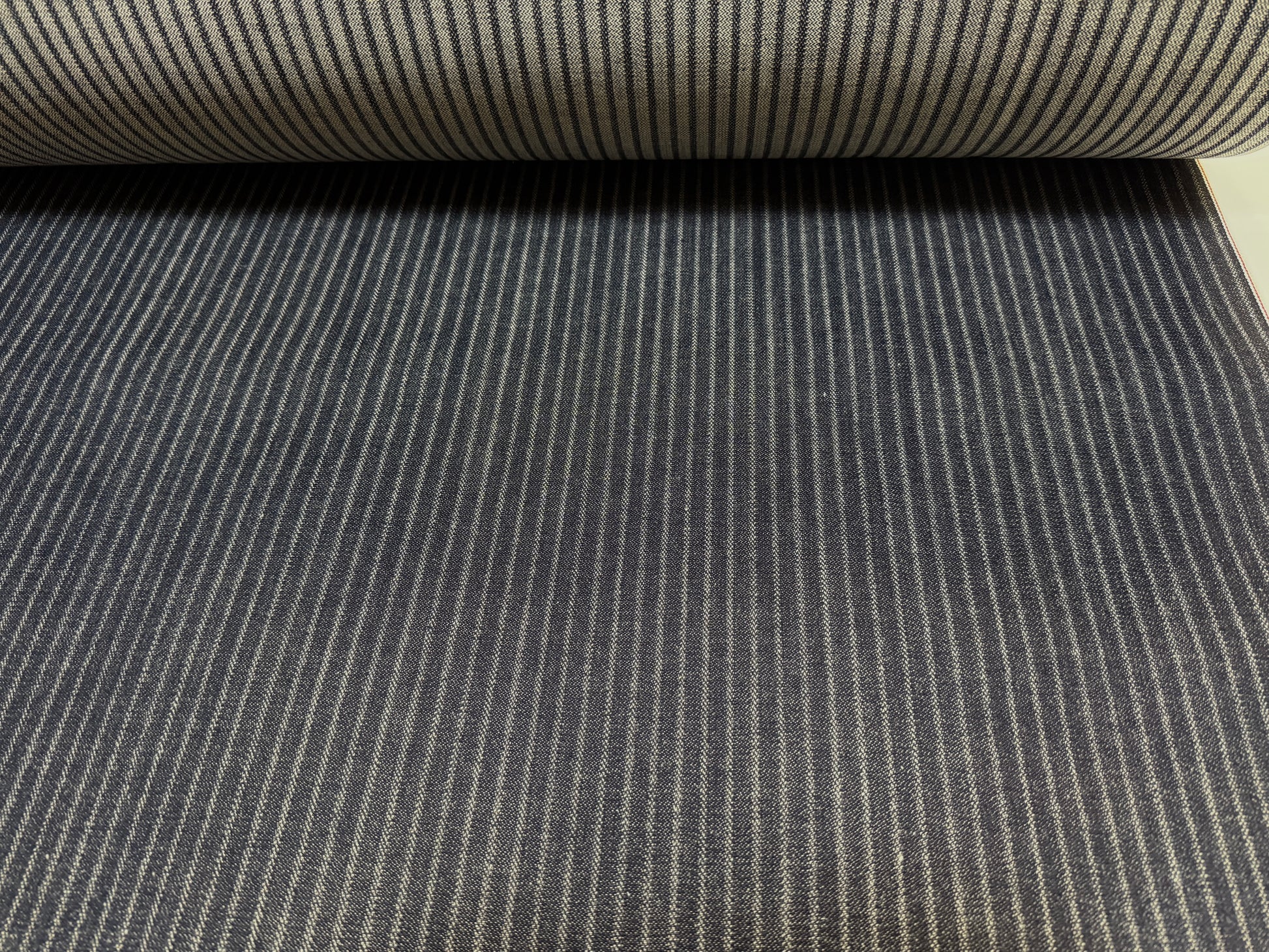 Okayama Denim black hickory selvage fabric roll showing fine stripes and smooth texture.