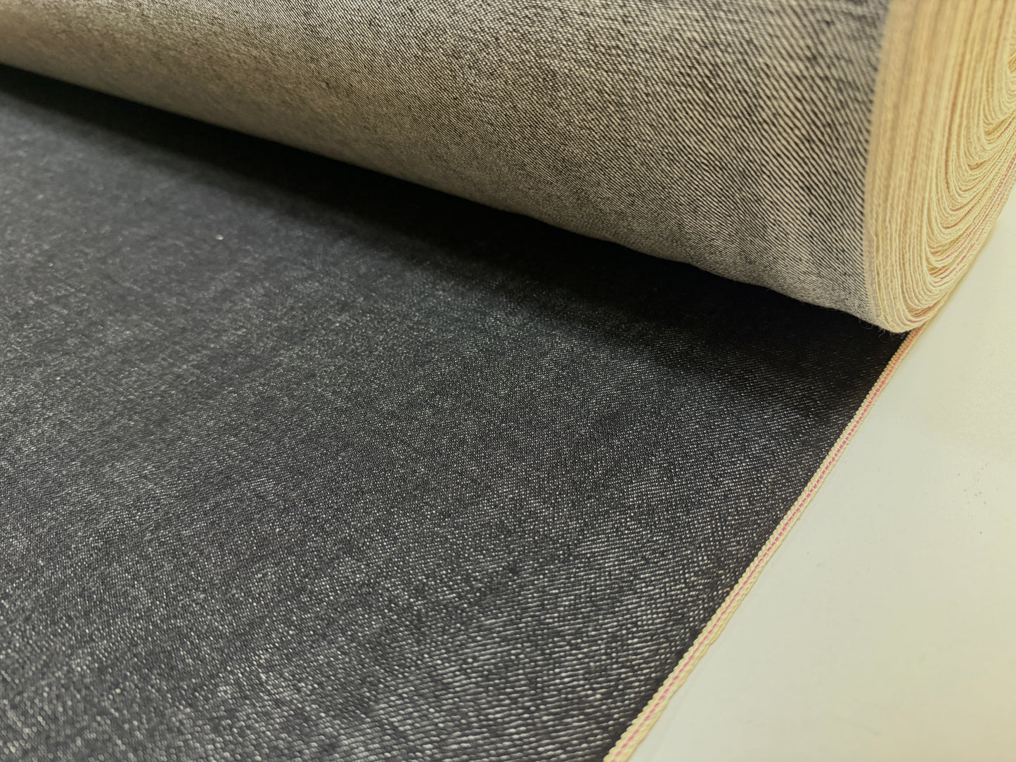 Okayama Denim 14.6oz Japanese Cotton Black Selvage Denim fabric rolled and ready for use.