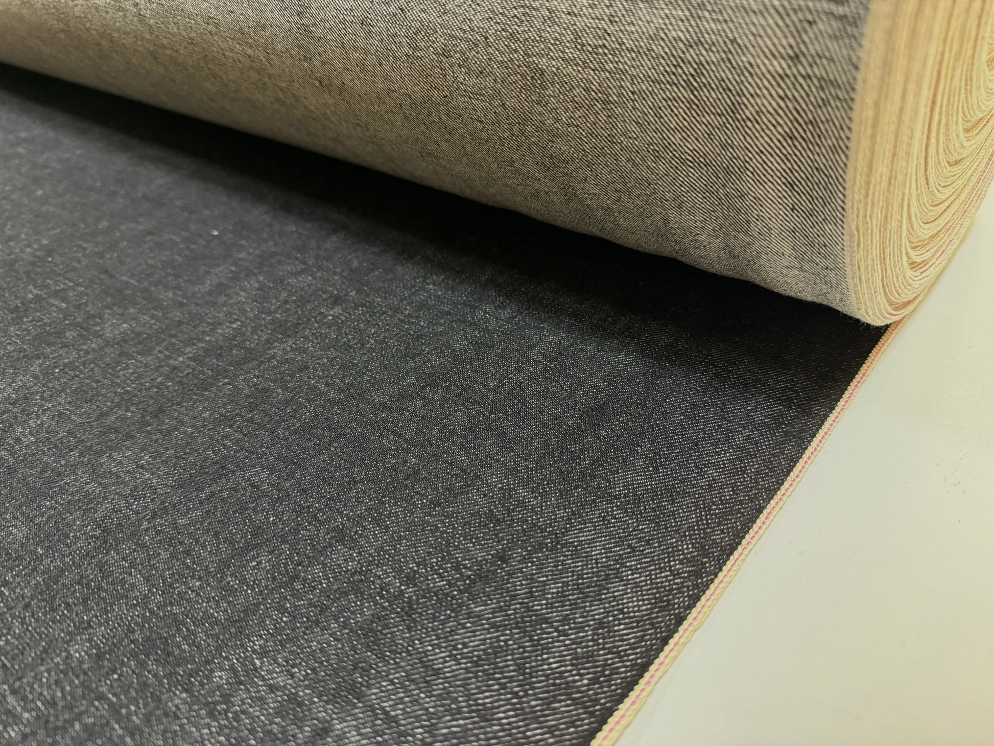 Okayama Denim 14.6oz Japanese Cotton Black Selvage Denim fabric rolled and ready for use.