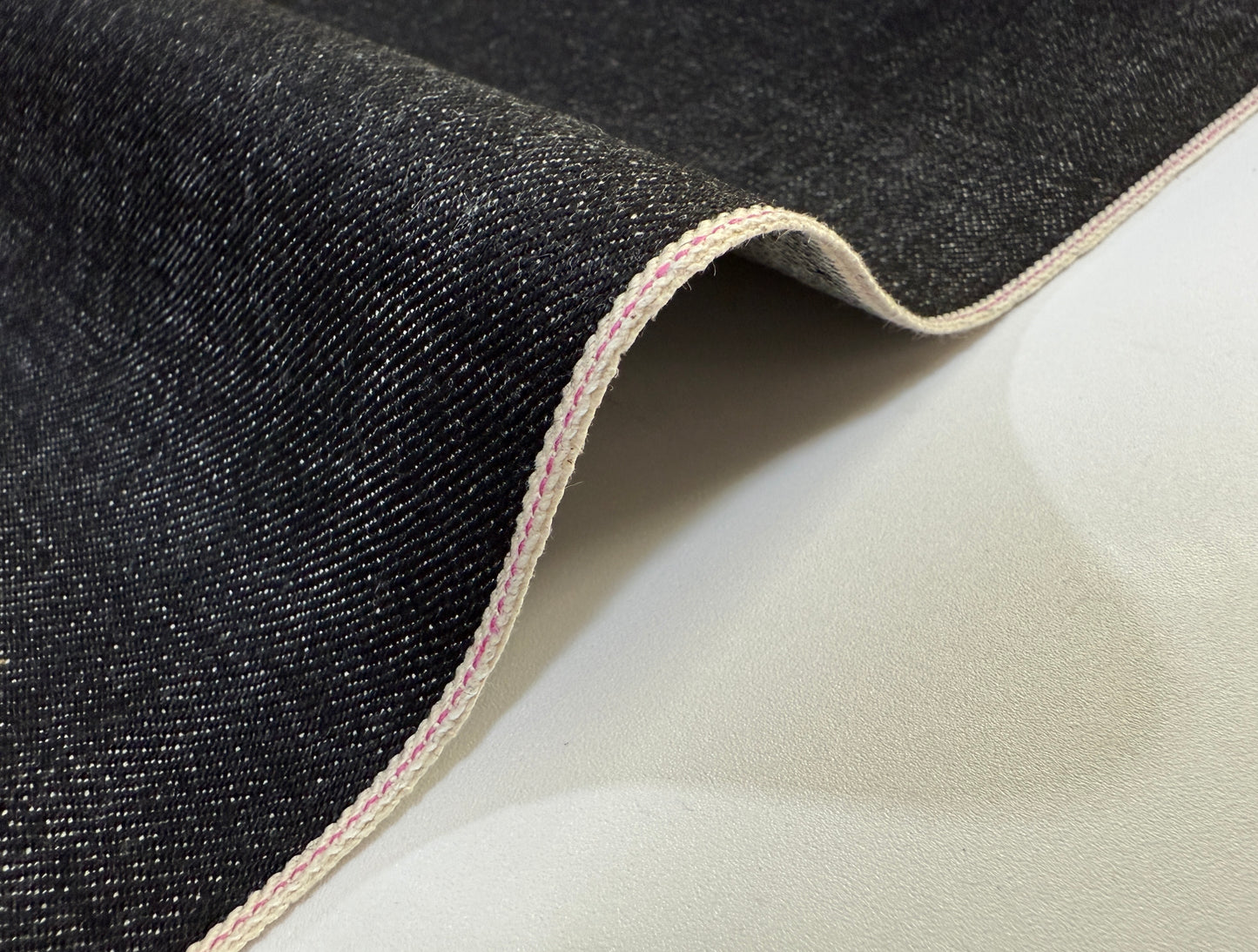 Okayama Denim 14.6oz Japanese Cotton Black Selvage Denim fabric showing smooth texture and edge stitching.