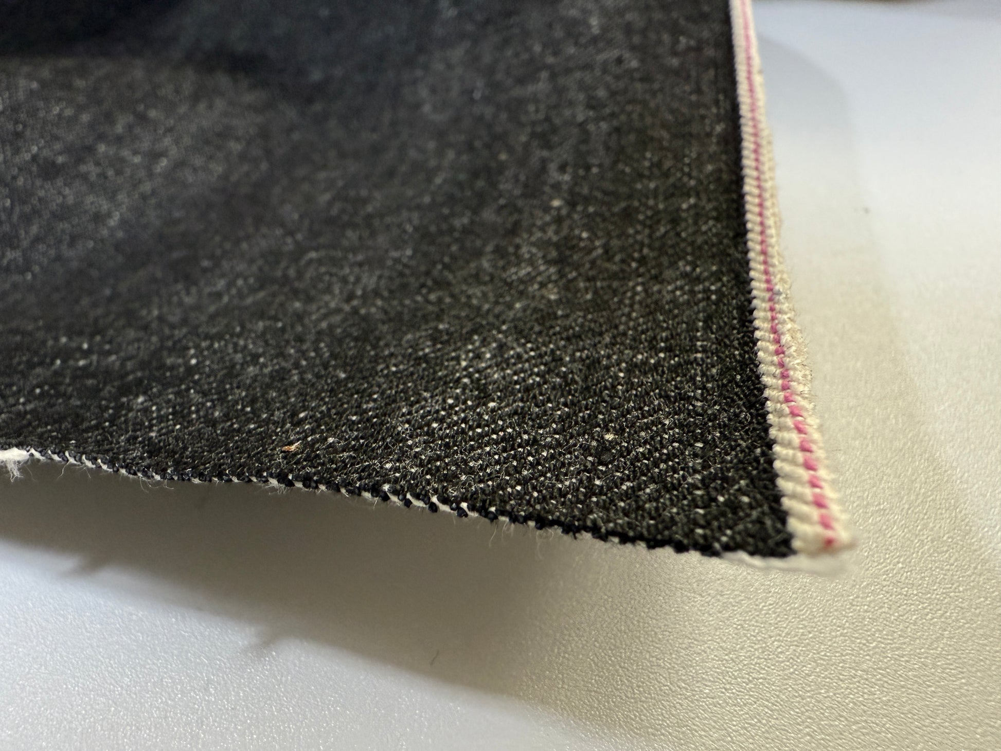 Okayama Denim fabric showcasing 14.6oz black selvage with unique selvedge edge detail.