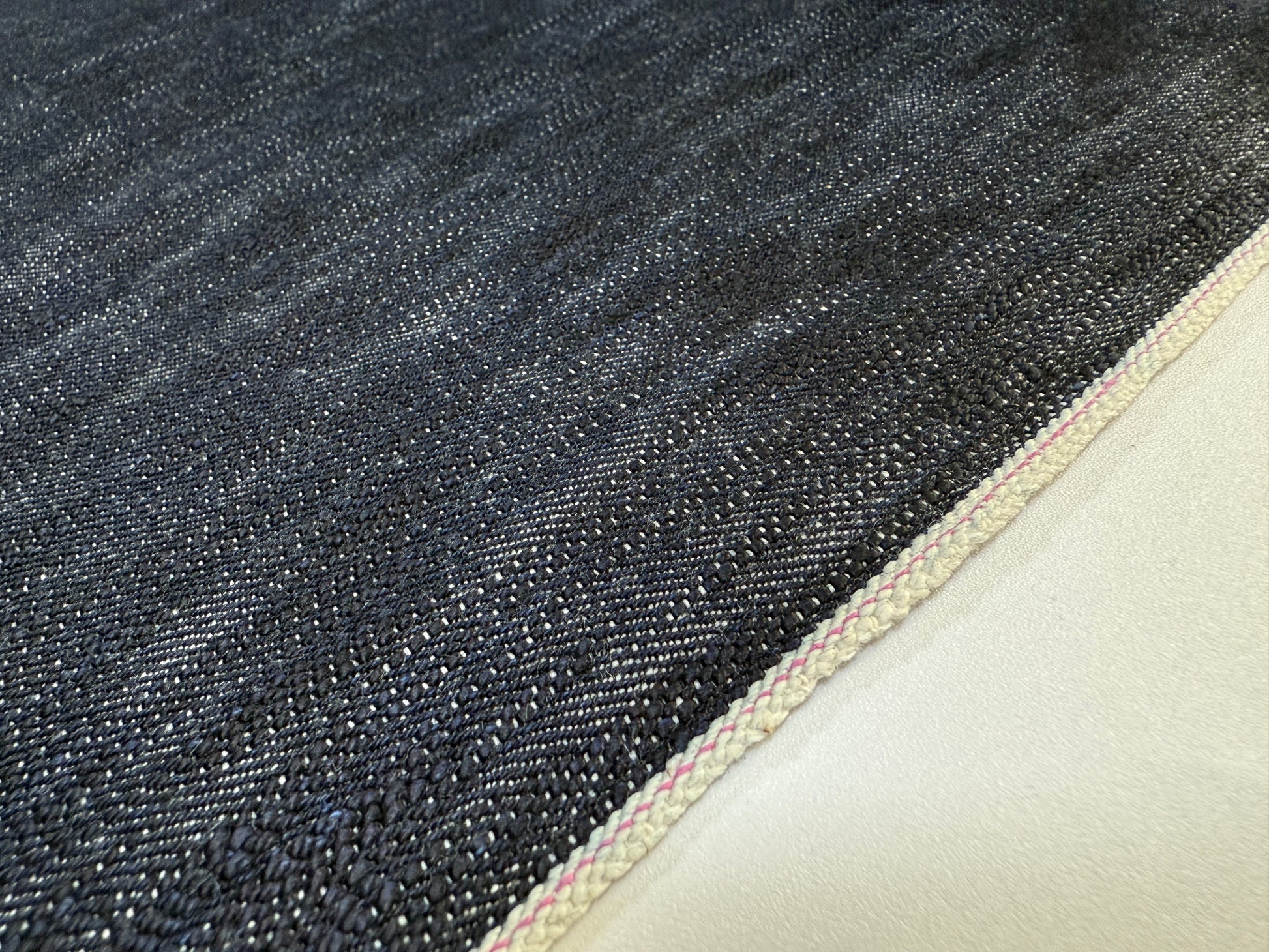 Okayama Denim 16.5oz Japanese Indigo uneven dyed slab selvage denim fabric close-up showing texture and selvage edge.