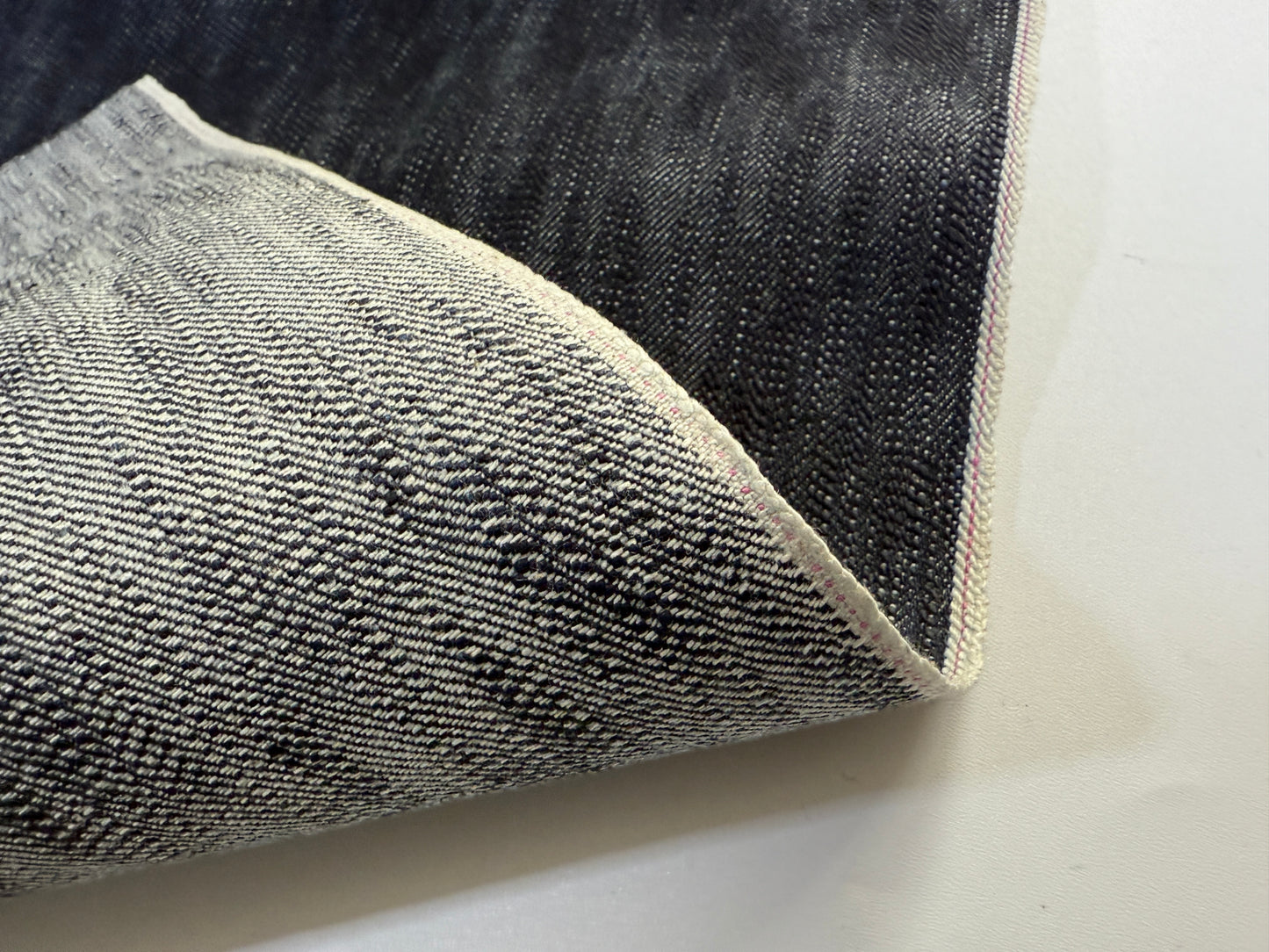 Okayama Denim showcasing 16.5oz Japanese indigo uneven dyed slab selvage denim fabric with unique texture.