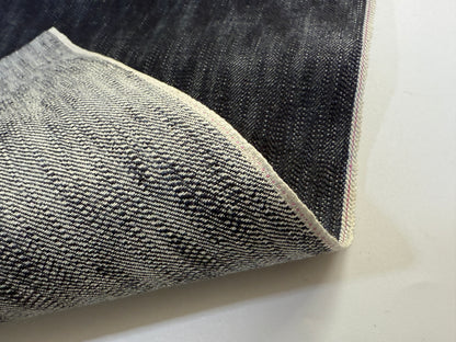Okayama Denim showcasing 16.5oz Japanese indigo uneven dyed slab selvage denim fabric with unique texture.
