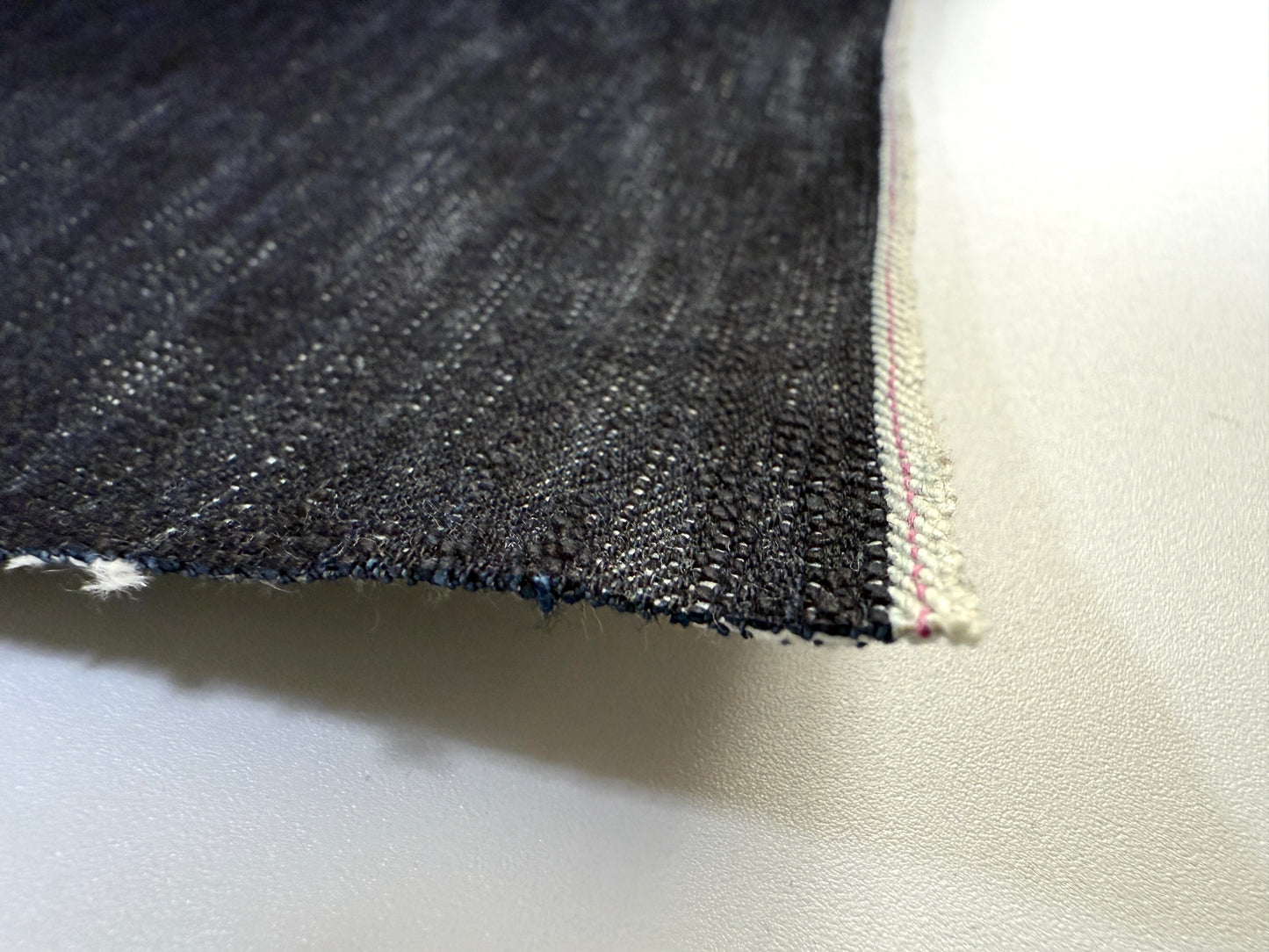 Okayama Denim close-up of 16.5oz Japanese indigo uneven dyed slab selvage denim showing texture and edge detail.