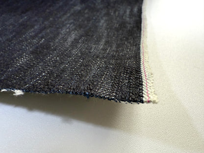 Okayama Denim close-up of 16.5oz Japanese indigo uneven dyed slab selvage denim showing texture and edge detail.