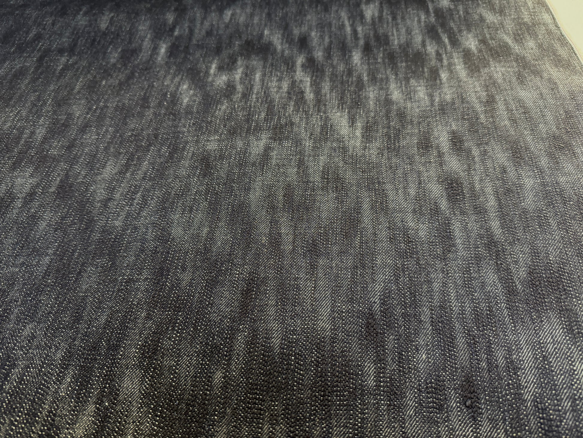 Okayama Denim fabric close-up showing the unevenly dyed texture of 16.5oz Japanese indigo slab selvage denim.