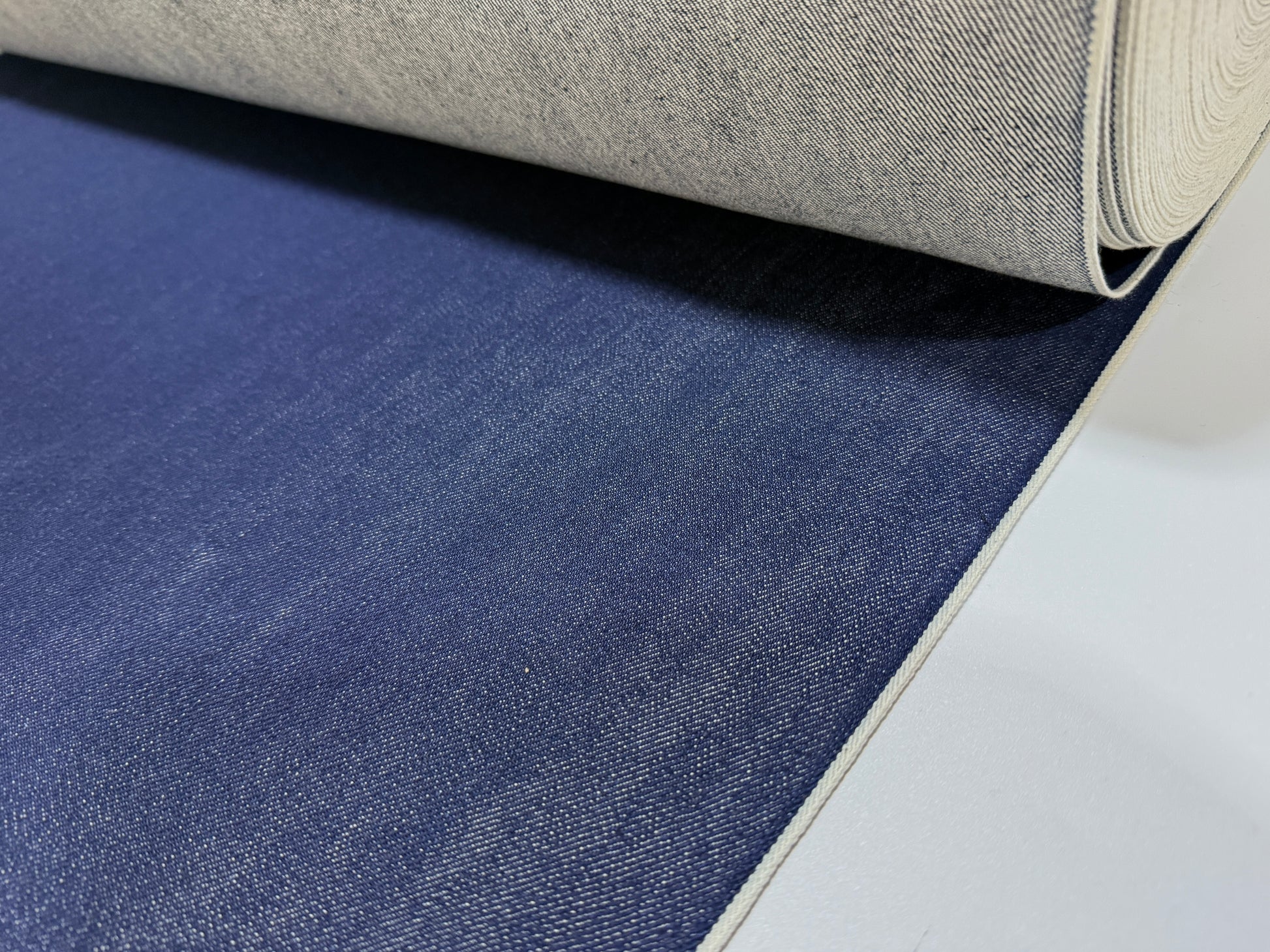 Okayama Denim 15 oz indigo selvage fabric rolled showing smooth texture and deep blue color.
