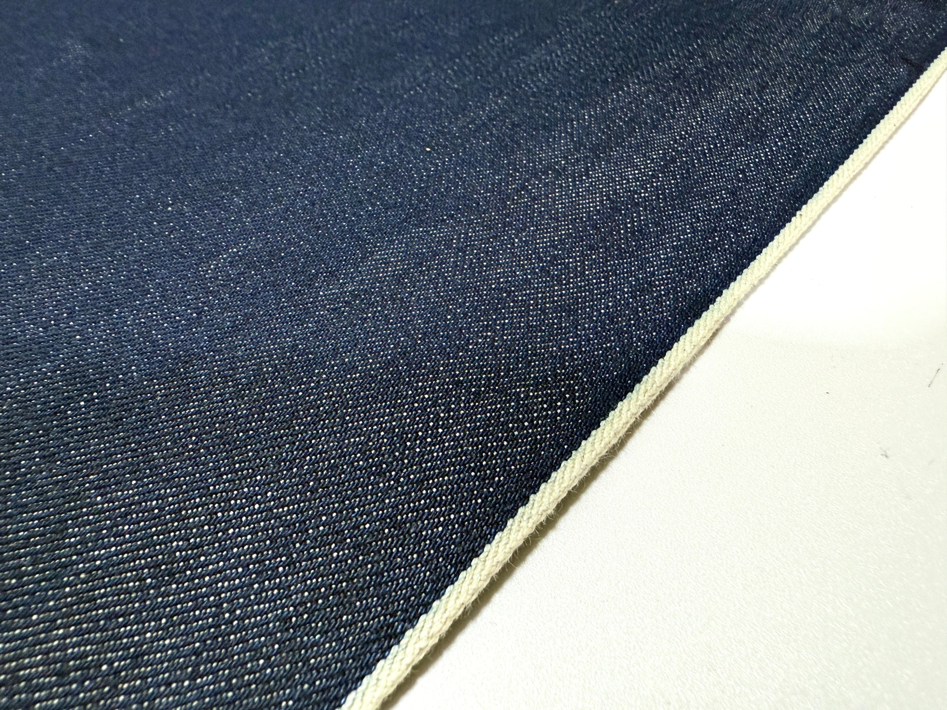 Okayama Denim | 15oz indigo selvage Japanese blue fabric showcasing smooth texture and white selvage edge.