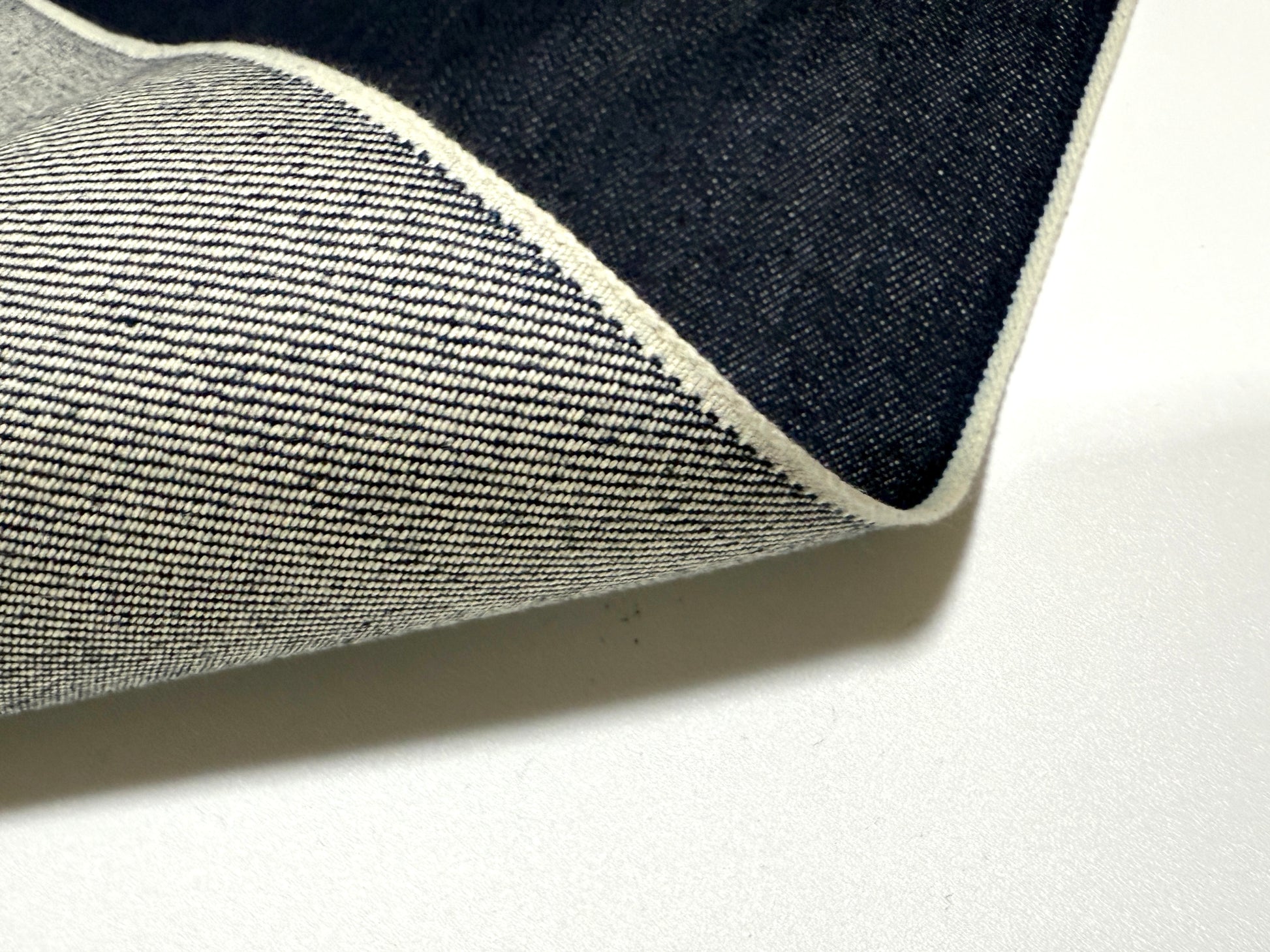 Okayama Denim | 15oz indigo selvage fabric showing smooth texture and blue selvage edges.