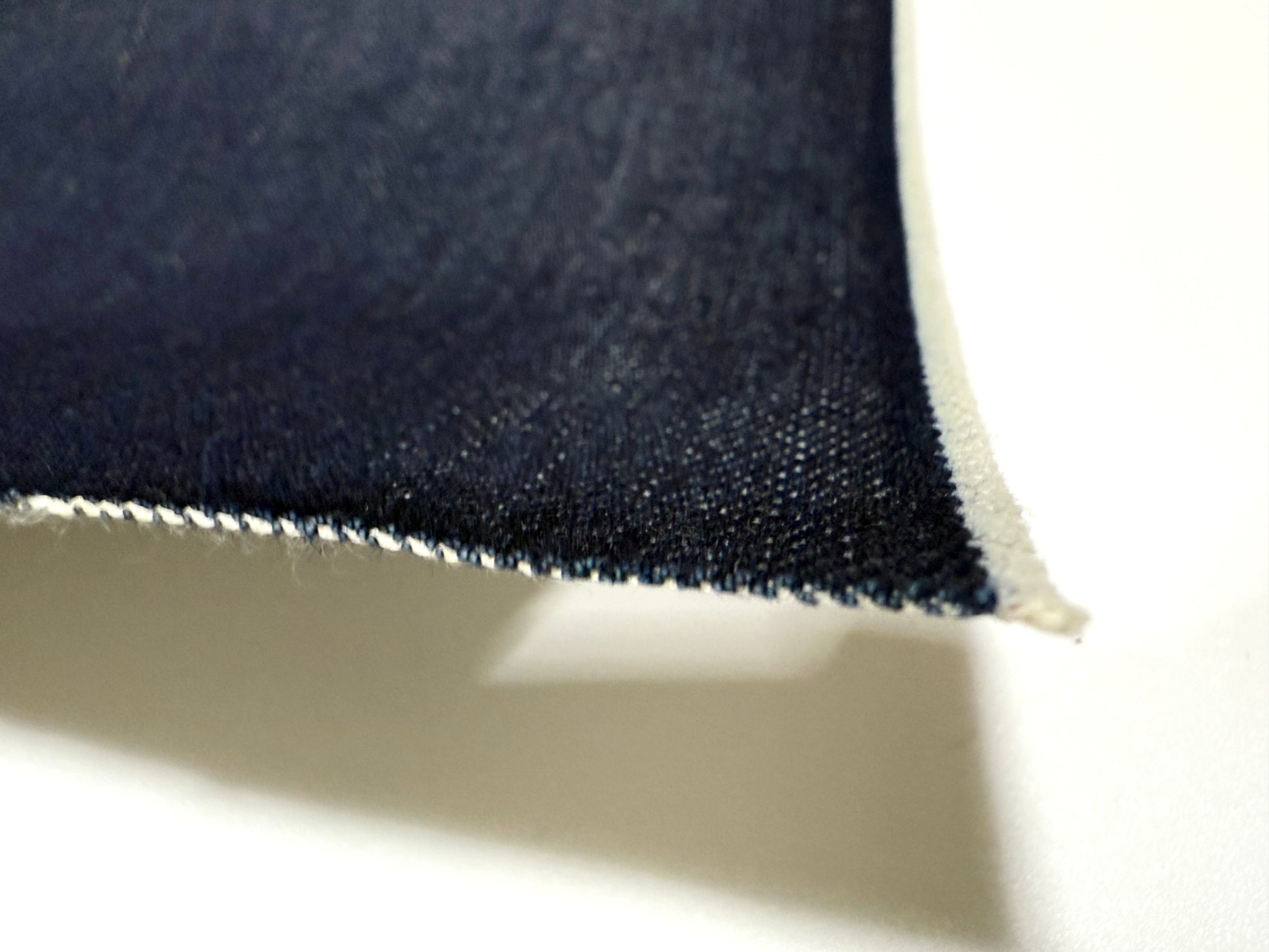 Okayama Denim fabric showcasing 15oz indigo selvage with smooth texture and blue edges.