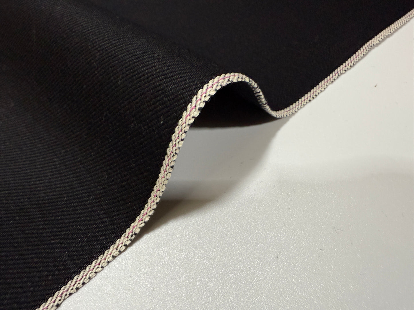 Okayama Denim | 14.6oz double-sided black Japanese selvage fabric with smooth texture and signature edge.