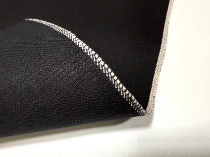 Okayama Denim | 14.6oz double-sided black Japanese selvage fabric showcasing a smooth texture and distinctive edge.