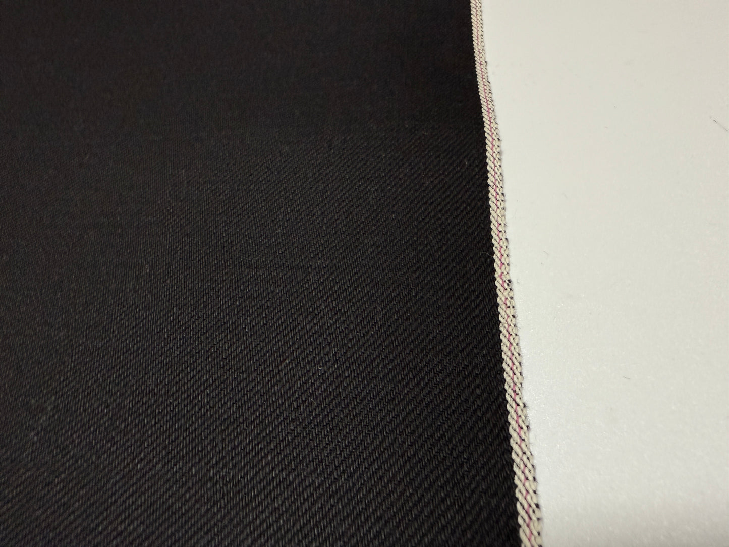Close-up of Okayama Denim | 14.6oz double-sided black Japanese selvedge fabric showcasing its smooth texture.