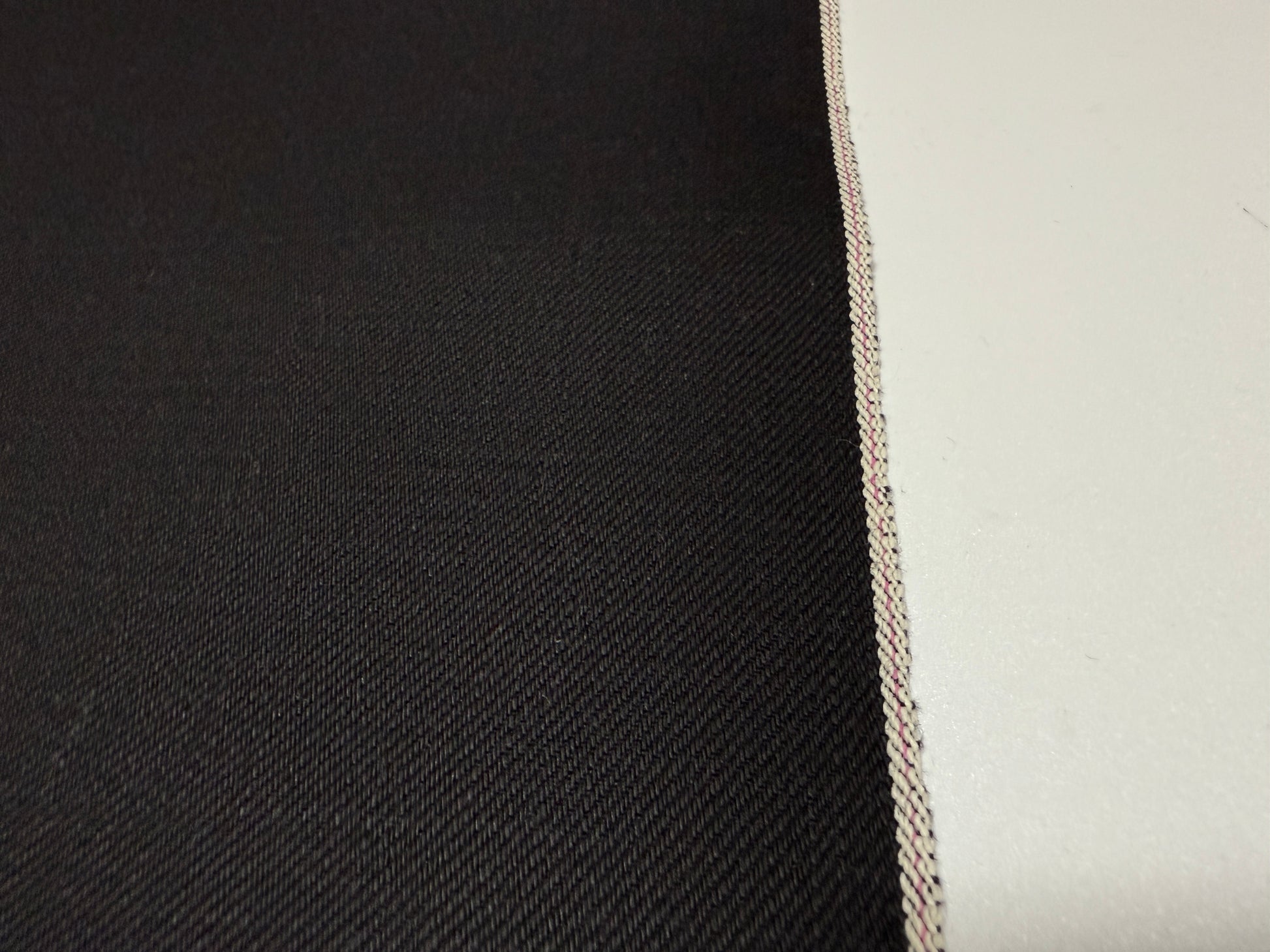 Close-up of Okayama Denim | 14.6oz double-sided black Japanese selvedge fabric showcasing its smooth texture.