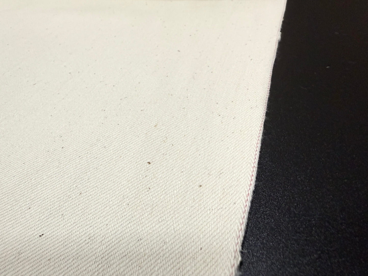 Close-up of Okayama Denim 13 oz ecru selvage fabric showcasing its soft texture and quality craftsmanship.