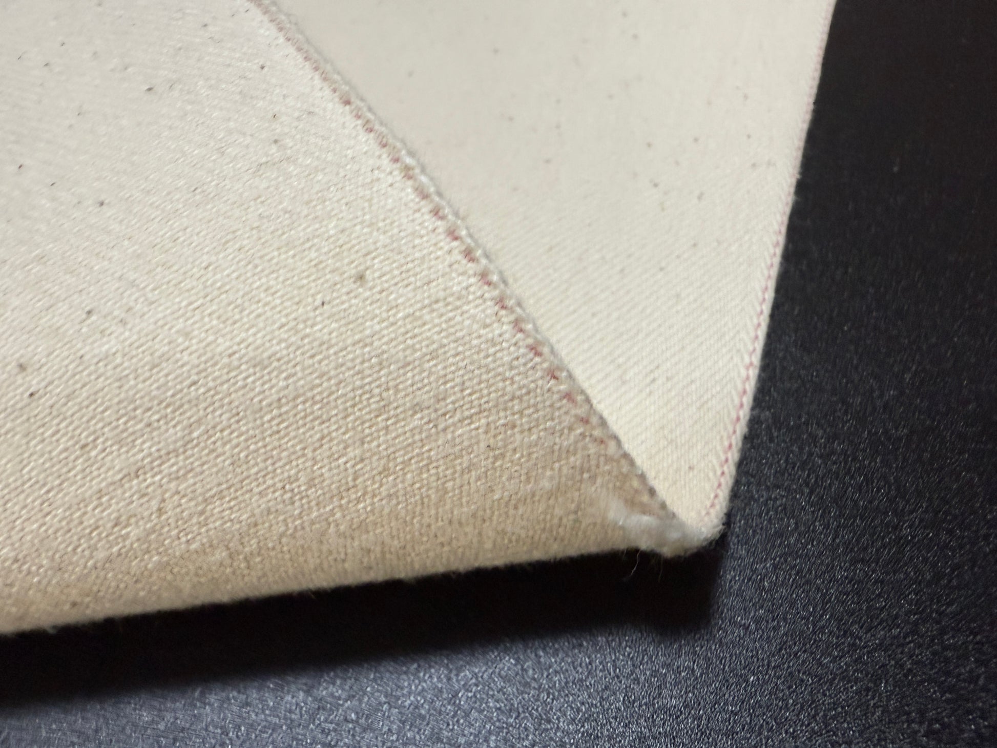 Close-up view of Okayama Denim 13 oz Ecru Japanese selvedge fabric showcasing its texture and stitching.