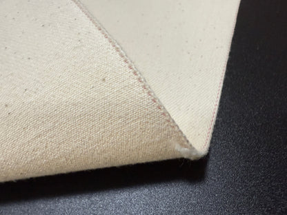 Close-up view of Okayama Denim 13 oz Ecru Japanese selvedge fabric showcasing its texture and stitching.