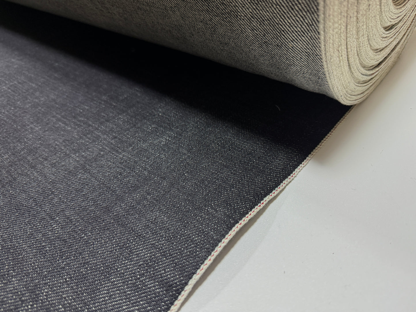 Okayama Denim roll showcasing 20 oz Japanese heavy ounce indigo selvage denim fabric with rich texture.