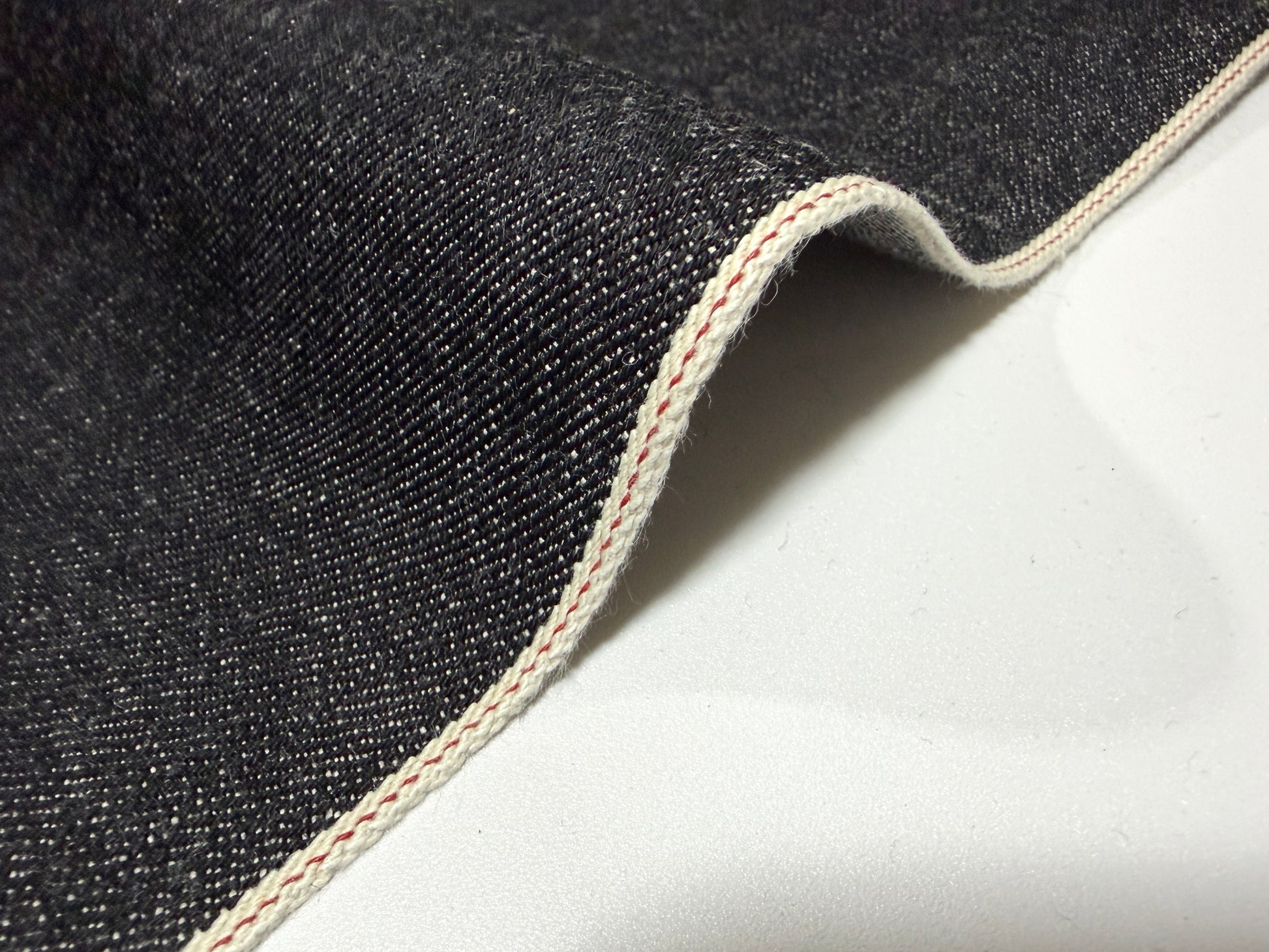 Close-up of Okayama Denim 14.5 oz Black Selvage Japanese Denim showcasing smooth texture and selvedge edge.