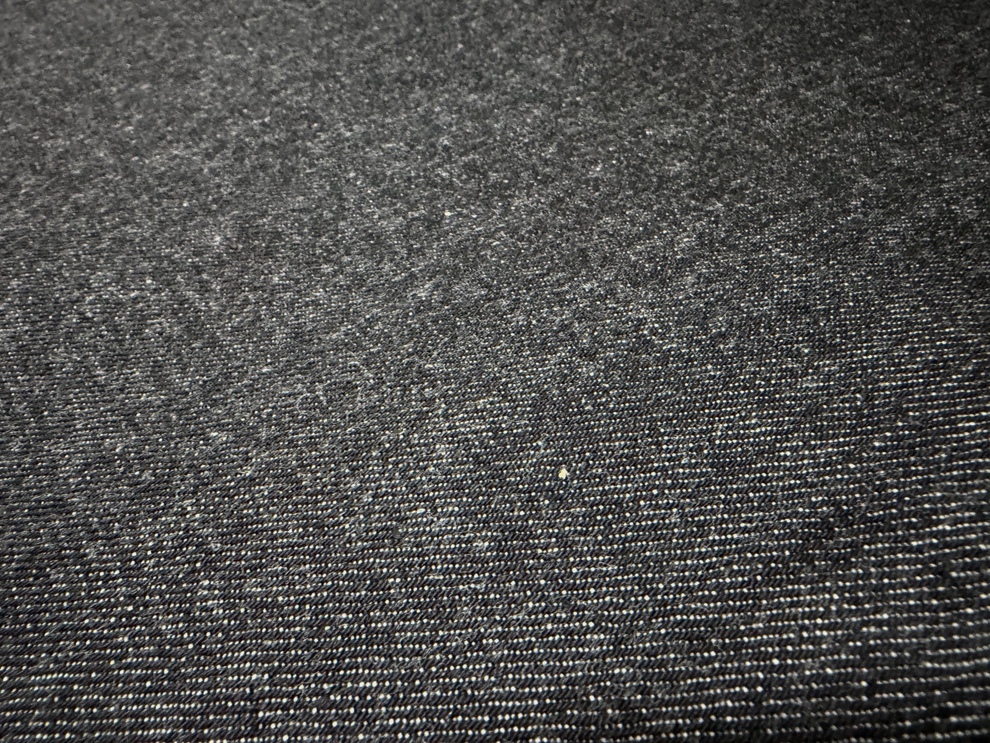Close-up of Okayama Denim 14.5oz Japanese cotton black selvage denim fabric showcasing texture and quality.