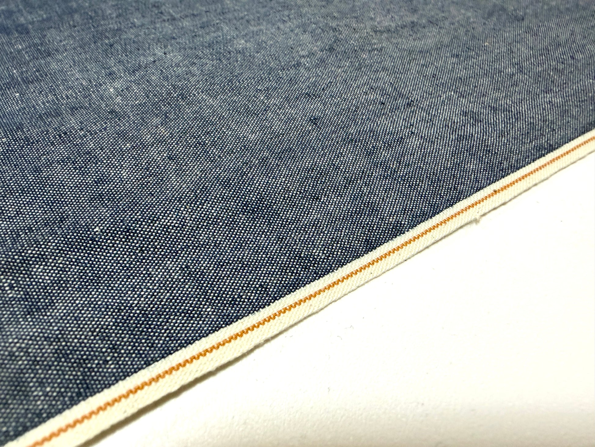Okayama Denim 4.5 oz Japanese indigo selvage chambray fabric close-up with a crisp edge.