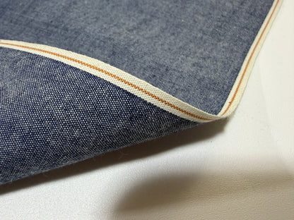 Okayama Denim - Close-up of 4.5 oz Japanese indigo selvage chambray fabric showcasing its unique selvedge edge.