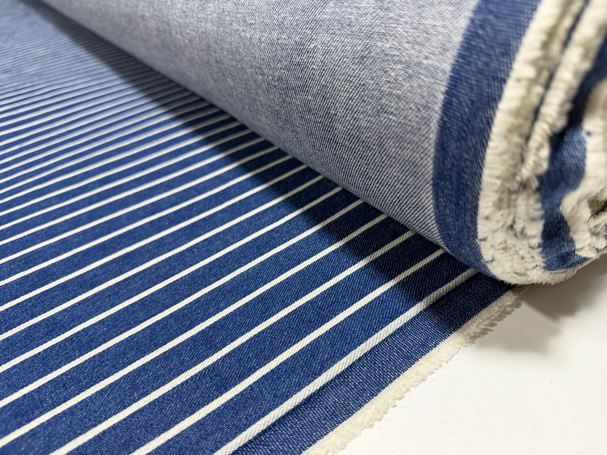 Okayama Denim Japanese indigo cotton fabric with discharge printed stripes on a roll.