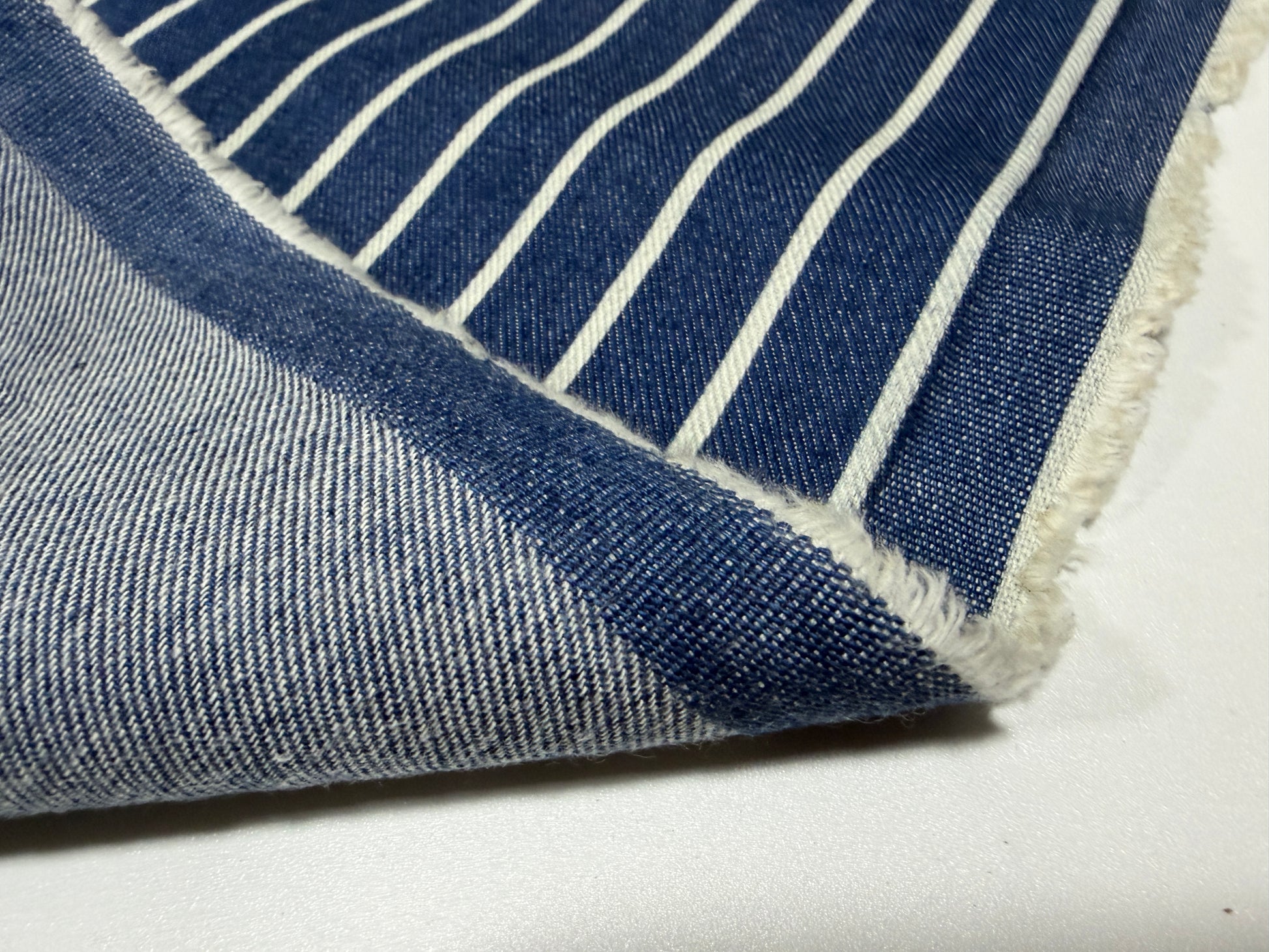 Okayama Denim fabric showcasing Japanese indigo cotton discharge printing stripes in a close-up view.