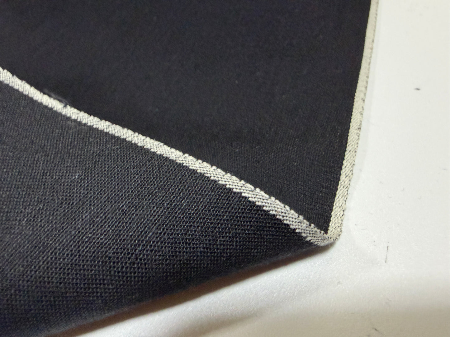 Close-up of Okayama Denim fabric showcasing the selvedge edge and soft black texture.