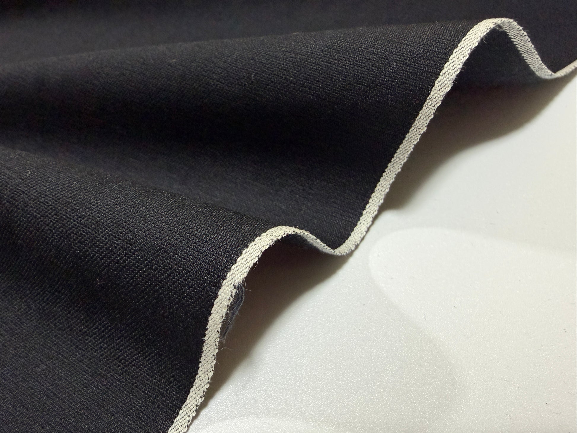 Close-up of Okayama Fabric, a 5 oz double-sided black shirt-weight fabric showcasing selvedge edges.