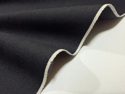 Close-up of Okayama Fabric, a 5 oz double-sided black shirt-weight fabric showcasing selvedge edges.