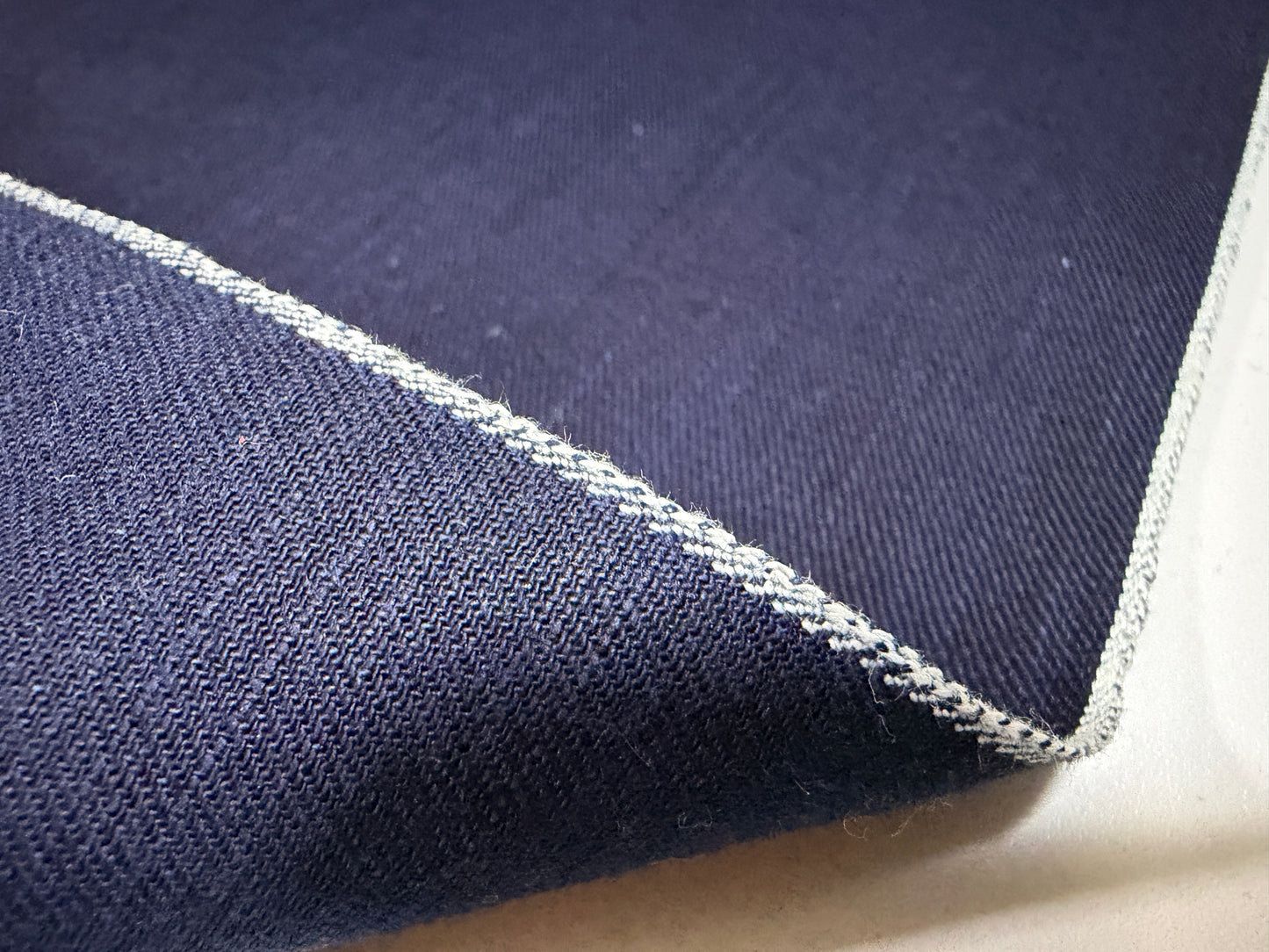 Okayama Fabric showing the texture and selvedge edge of 6.5 oz double-sided indigo shirt-weight fabric.