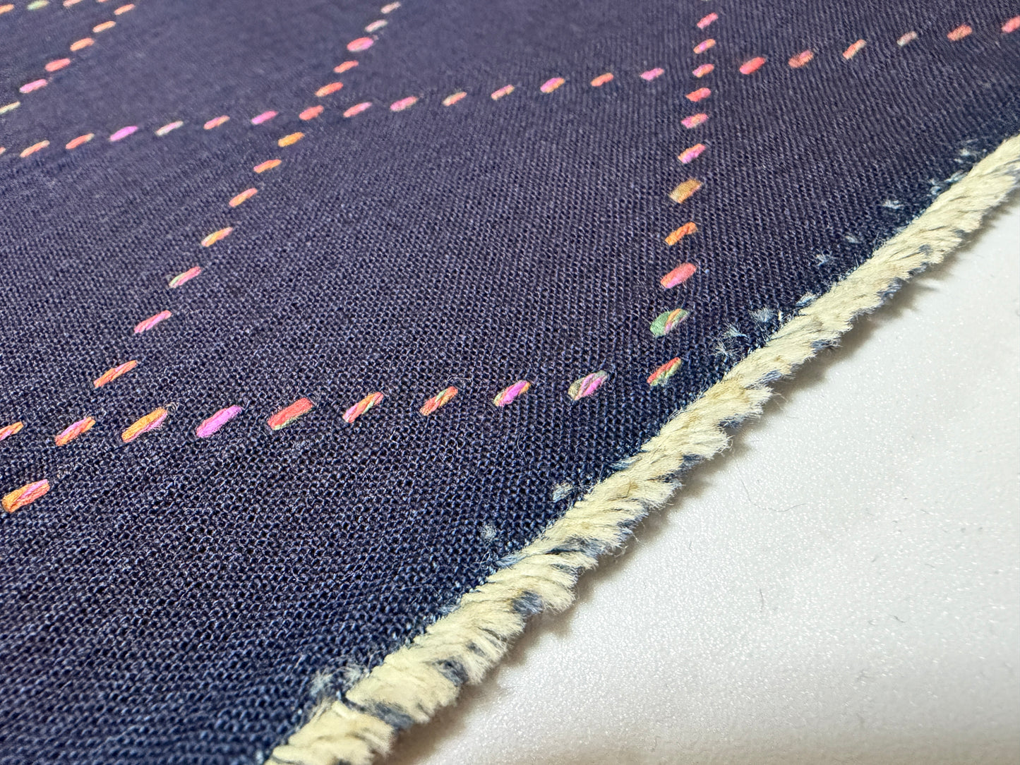 Okayama Denim 7 oz Sashiko fabric with colorful multi-color stitching and frayed edge detail.