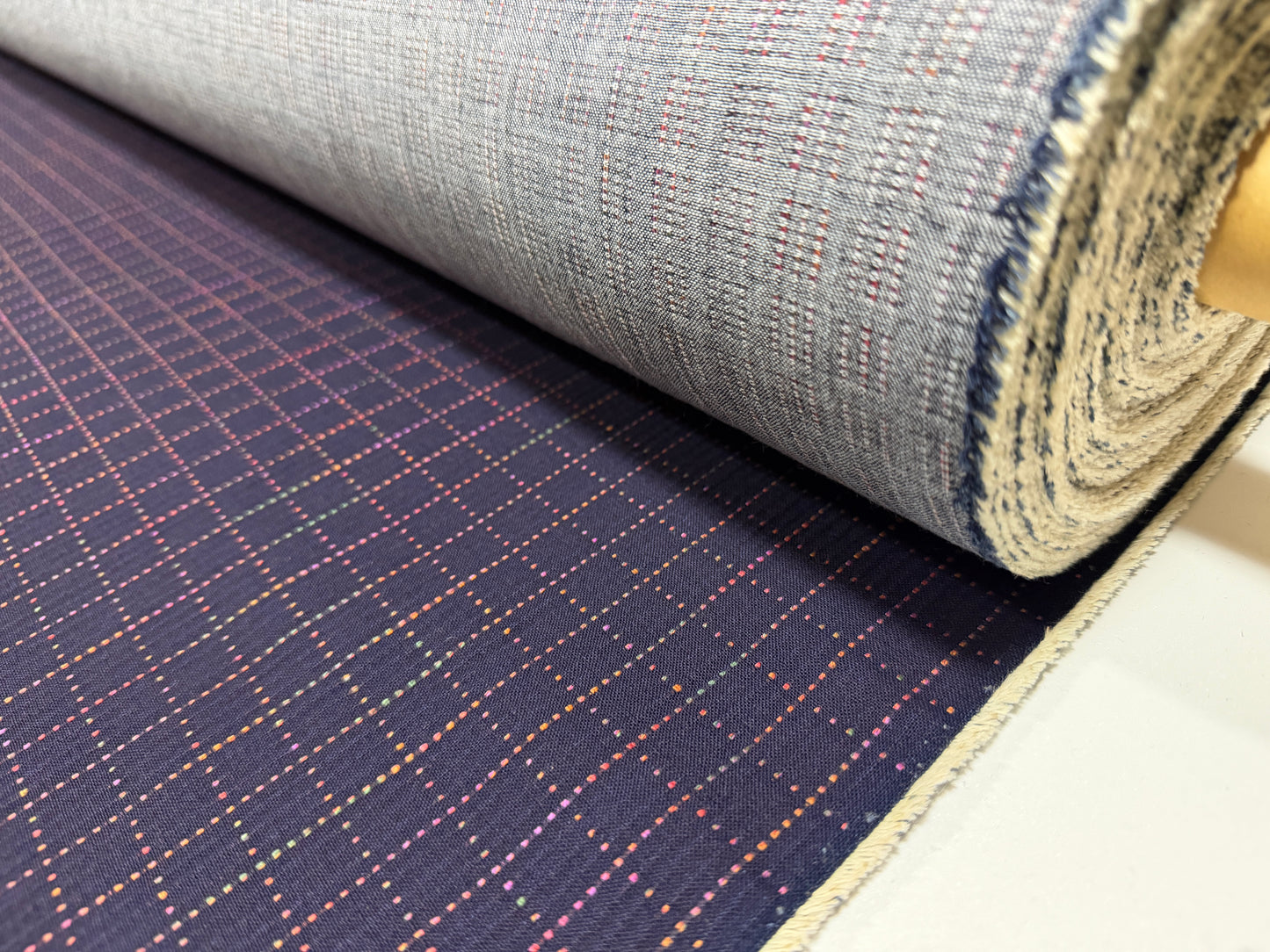 Okayama Denim 7 oz Sashiko Grid Cotton Fabric featuring colorful stitching and unique pattern, rolled and ready for use.