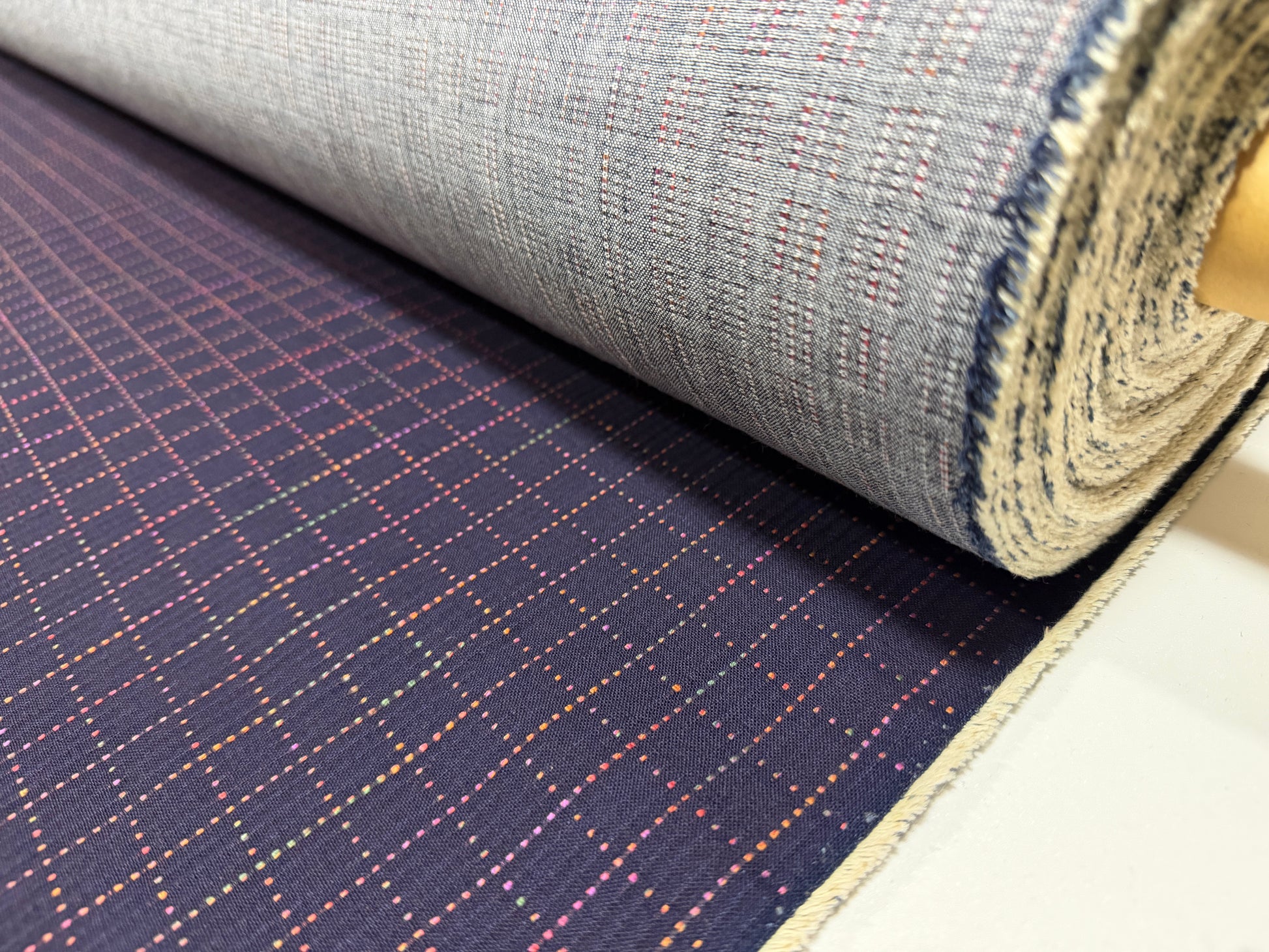 Okayama Denim 7 oz Sashiko Grid Cotton Fabric featuring colorful stitching and unique pattern, rolled and ready for use.